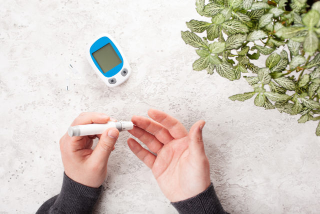 man hands using lancet on finger to check blood sugar or ketones level by glucose meter. medicine diabetes keto diet health care at home