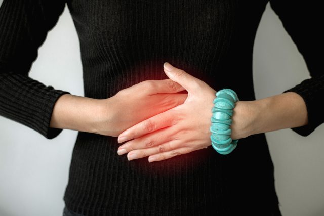 Woman hand holding on stomach suffering from abdominal pain,Female with having menstrual period cramp,Food poisoning,Close up