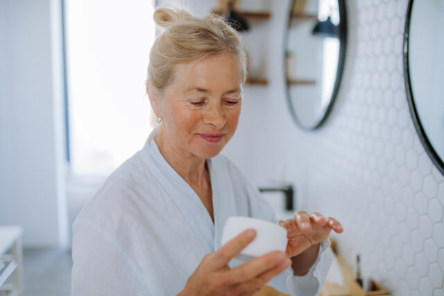 A beautiful senior woman applying natural cream