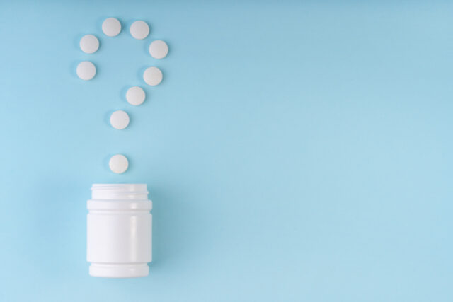Question sign, mark from pharmaceutical medicine pills. Creative layout of tablets and bottle on blue. Question symbol. Medicine FAQ, healthcare concept. Choice metaphor. Copy space, flat lay