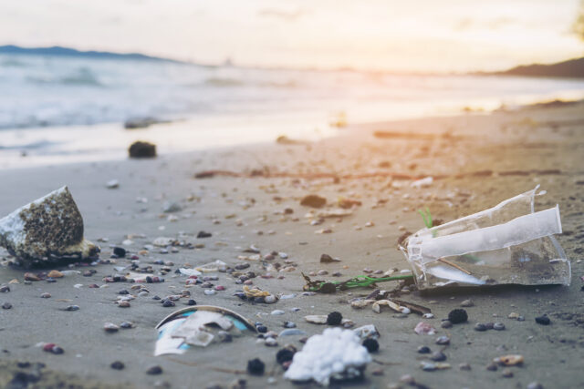 Microplastics and trash on sand beach showing environmental pollution problem