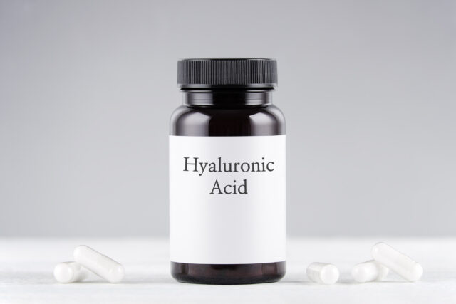 nutritional supplement hyaluronic acid bottle and capsules on gray background