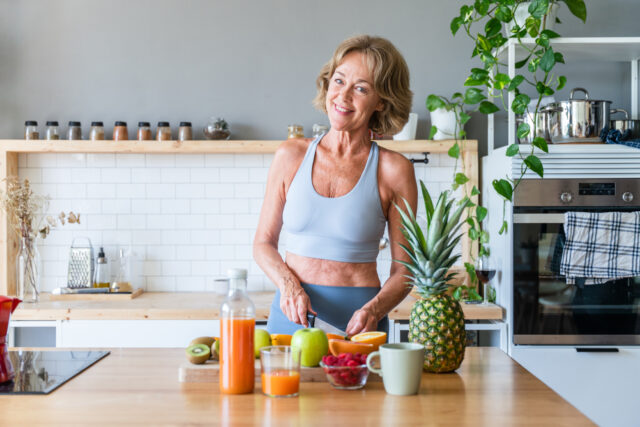 Beautiful mature senior woman at home, domestic life and leisure moments - 50-60 years old pretty female adult wearing sportswear eating healthy food after fitness workout