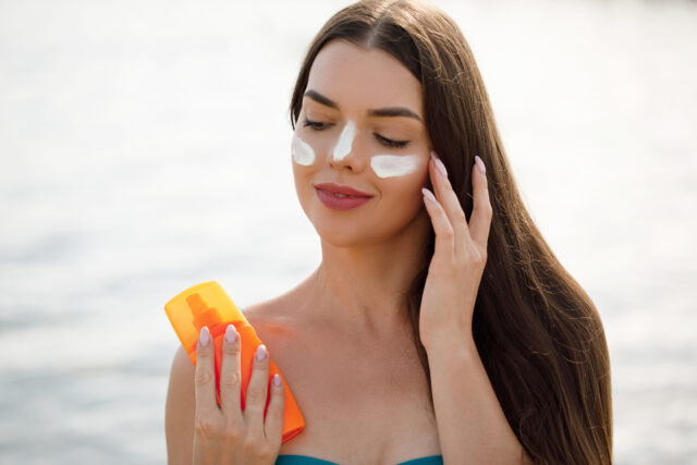 Woman smile applying sun cream on face. Skincare. Body Sun protection. sunscreen. Female smear moisturizing lotion on skin.
